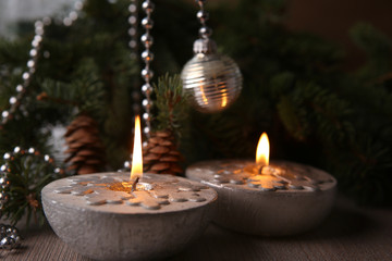 Christmas decoration. Silver Christmas candles decorated with snowflakes near christmas tree, garlands. Candlelight.