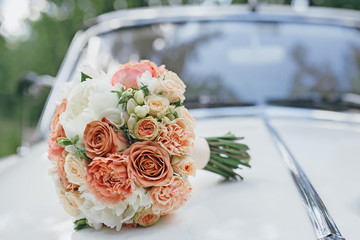 Wedding bouquet on the hood of a white retro car