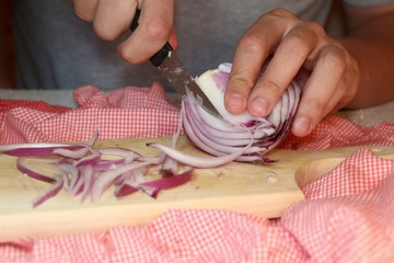 Unrecognizable man cutting purple onion. Selective focus.
