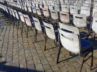 Vintage old chairs organized in rows on cobblestone surface