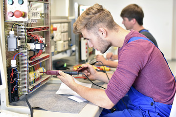 Two electrician students working at electrical panel
