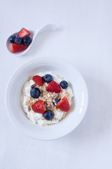 muesli with berries and yogurt on a white backgrund