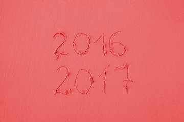 2016 and 2017 written on sand at the beach in red colors. Greeting card