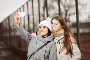 Two teenage girls in autumn outdoors taking a selfie