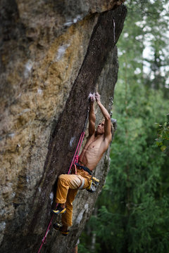 Male rock climber struggles to reach his next grip on a steep cliff. Extreme sport.