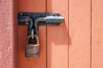 Old rusty padlock on old wooden door.