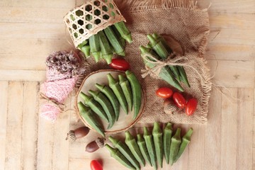 Fresh okra pods and sliced on wood background.