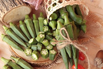 Fresh okra pods and sliced on wood background.