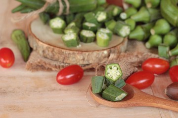 Fresh okra pods and sliced on wood background.