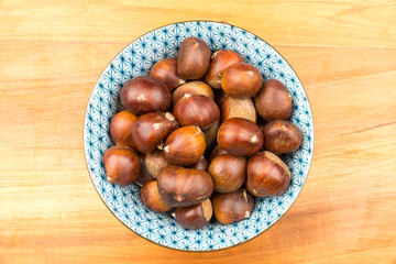 Obraz premium Spanish Chestnuts in a vintage dish on wooden plate background