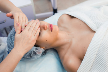 Fototapeta na wymiar Smiling brunette enjoying a head massage in the health spa