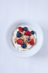 muesli with berries and yogurt on a white backgrund