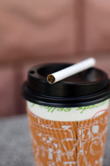 Cigarette next to plastic cup