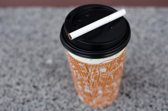Cigarette next to plastic cup