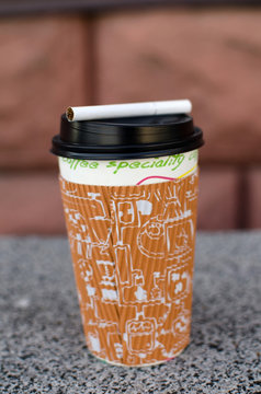 Cigarette next to plastic cup