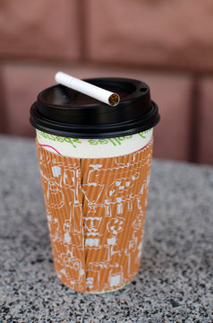 Cigarette next to plastic cup