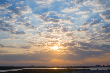 Rays of the sun illuminate the cloudy sky.