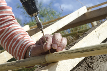 Male hands inserting a screw in the construction with a drill