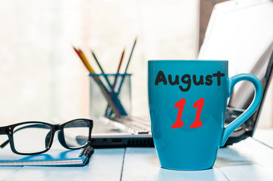August 11th. Day 11 of month, morning coffee cup with calendar on freelance workplace background. Summer time. Empty space for text