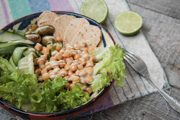 healthy salad in a bowl. olives, lime, chickpeas, cucumber  and tahini. more greens every day