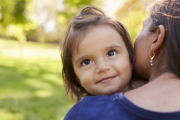 Mixed race mother holding her daughter, over shoulder view