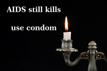 Information against AIDS and the use of condoms with lit candle on black background.