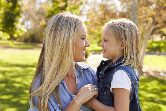 Blonde woman and her young daughter in a park side view