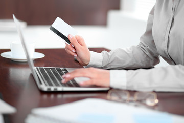 Close up of business woman hands using credit card and laptop computer