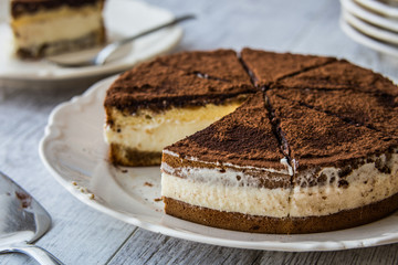 Homemade Tiramisu Cake on a white wooden surface.