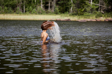 Beautiful girl splashing her hear in an Swedish forest lake
