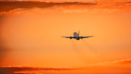 Airplane in the air and sunset in background
