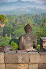 Stone Buddha looking to the jungle from Borobudur temple, morning Indonesia