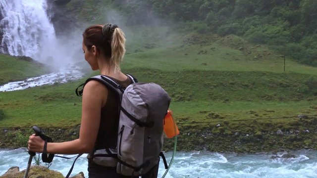 Woman hiker with backpack walking on the wild track near Vettisfossen waterfall. Norway.