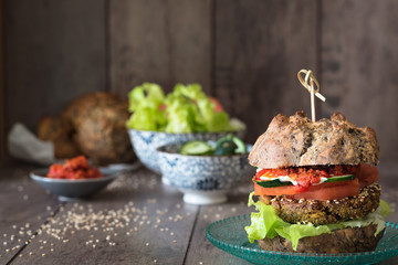 Veggie-Burger, Gemüse und Saucen Schälchen mit Zutaten auf dem Holzhintergrund