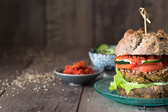 hamburger vegetariano con pane alle olive fatto in casa; verdure e salse in ciotole di ceramica. Sfondo rustico di legno. Spazio per scrittura