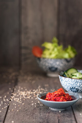 salsa per condire hamburger vegetariano in primo piano e ciotole con verdure sullo sfondo. Immagine verticale con spazio per scrittura