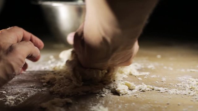 Baker kneading dough in flour on table