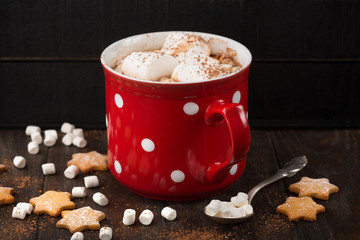 Big red Cup of hot Chocolate drink with Marshmallows, gingerbread cookies and cinnamon on dark wooden background. Winter time. Holiday concept, Selective focus
