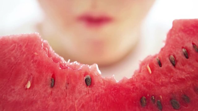 Little boy eats big red slice of a watermelon