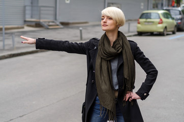 Young blonde woman catching the taxi 