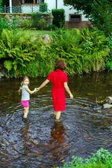 Mother with daughter crossing little river