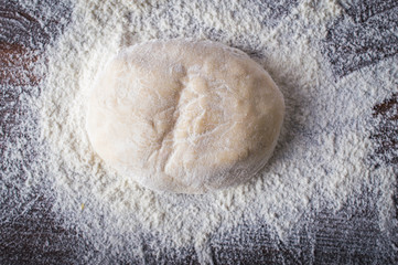 Kneaded dough on a layer of flour. On wooden background.Top view. Flat lay.