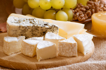 Various types of cheese served with grapes, walnuts and honey