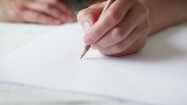 Sliding footage of an artist's hand sketching with a simple pencil
