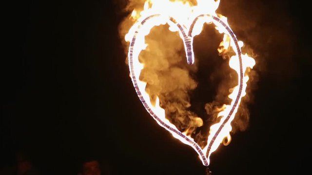 Fire show and fire heart at night on black background