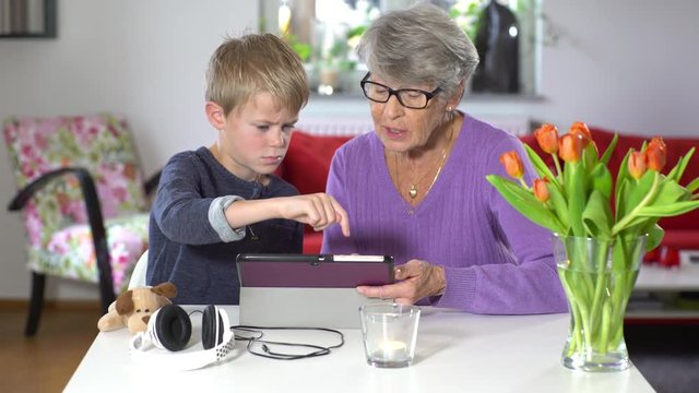 A grandmother and her grandson surfing the web using a tablet.