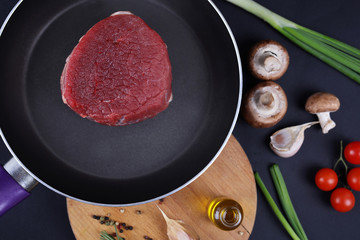 Raw beef meat stesk in nonstick frying Pan, spices, vegetables, olive oil. Cooking background, heathy eating concept.