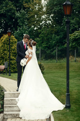 Bride and groom lean to each other tender standing on the path i