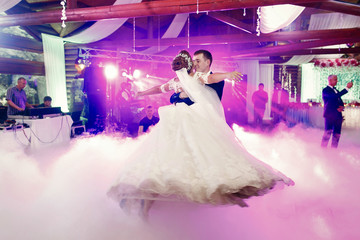 Bride spreads her hands while groom whirls her in smoke