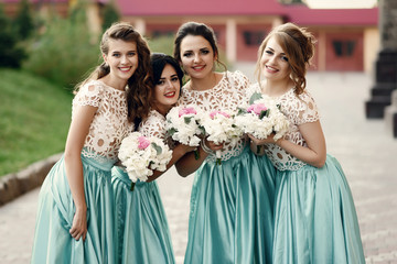 Naklejka premium Bridesmaids in white lace blouses lean to each other standing ou